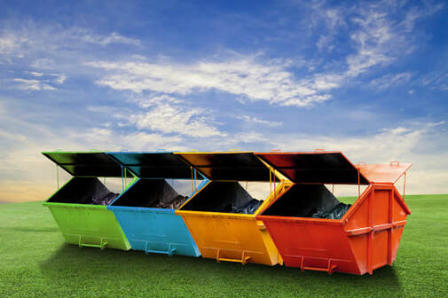 Four brightly coloured skips on a green lawn with a blue sky in the background. The lids of the skips are open and there is some waste inside each one. The skips are coloured green, blue, orange and red from left to right.