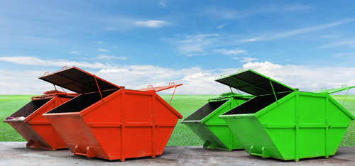 Two red skips and two green skips on a paved area in front of a green lawn. A blue sky is in the background. The red skips are on the left and the green skips are on the right. Two of the skips have their lids open.s 